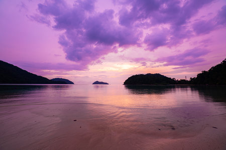 Aerial view of a stunning sunset above the Surin Islands. With golden hues reflecting on the calm ocean waters. The coral reef at the shoreline in the foreground adds depth.の写真素材