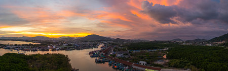 A breathtaking view of a vivid yellow, pink and purple sunset reflecting on calm sea. This serene scene captures the beauty of nature's colors at Phuket fishing port. colorful cloud scape backgroundの写真素材