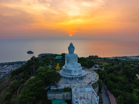 aerial view bright yellow sun in sunrise at Phuket big Buddha. the sun breaks through the clouds and illuminates the Buddha statue that atop the mountain.Sunrise with amazing light rays effects.の写真素材