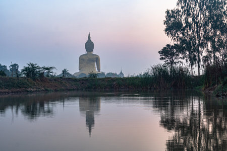 reflection of the Buddha in the swamp at sunrise. the great Buddha of Thailand is the largest Buddha statue in the world at wat Muang Ang Thong Thailand.の写真素材