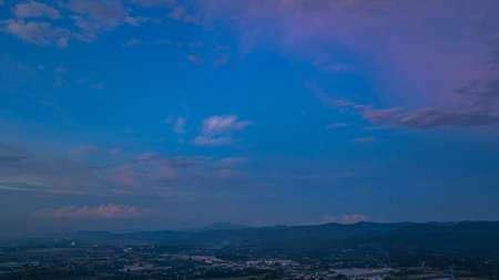 A dramatic view of a lush, forested mountain peak shrouded in thick clouds, capturing the raw beauty and mystique of nature under an overcast sky.の写真素材