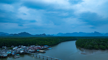 Aerial view of A small bridge connects to a fishing village that lives on a small island surrounded by mangrove forests. In front is a canal that leads to the sea, rich in various marine life.の写真素材