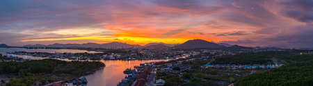 Aerial view of a amazing panoramic view of colorful sky over a large fishing port. This port is important as a center for large fishing boats. A stunning sunset sky reflected on the waterの写真素材