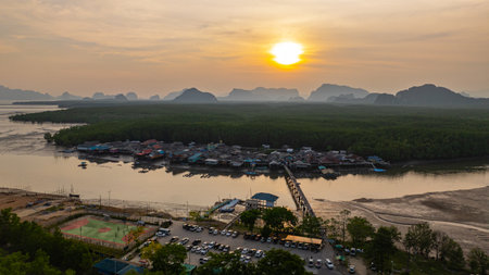 Aerial view of A small bridge connects to a fishing village that lives on a small island surrounded by mangrove forests. In front is a canal that leads to the sea, rich in various marine life.の写真素材