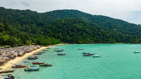 A stunning aerial view of a tropical beach village with rows of small huts along the coastline,...