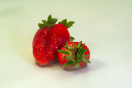 A close up of red strawberries kissed by morning dew, glimmering with natural shine. The image celebrates organic simplicity, freshness, and the nourishing essence of wholesome fruit.の写真素材
