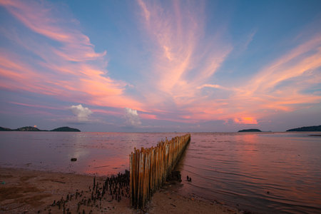 Under a radiant dusk sky, hues of orange and pink melt into tranquil waters. The lake captures every shimmer of the fading light offering a peaceful moment of reflection and harmony with nature.の写真素材