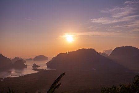 the flare light from the sun shines down on the islands. 
stunning aerial view of the beautiful Phang Nga Bay 
with Steep limestone hills protruding vertically from Thailand's emerald waters.の写真素材
