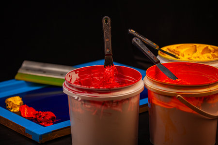 Colorful screen printing workshop scene where red, orange, and yellow inks merge across the mesh...