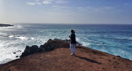 a girl on a rock in front of the sea of ââLanzaroteの写真素材