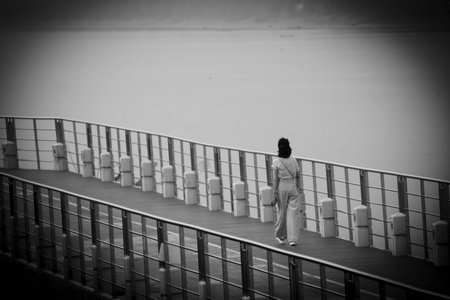 <p>Black and white photo of a woman walking on the bridge over the river</p>