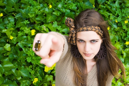 Pretty young girl sitting and pointing his finger at the camera の写真素材