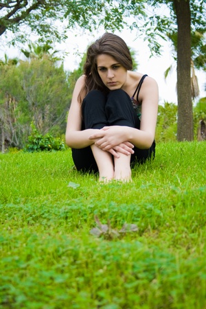 beautiful young girl sitting on the grass doing a yoga posture の写真素材