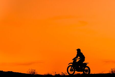 Black silhouettes Motocross rider on a motorcycle in front of colorful sunsetの写真素材
