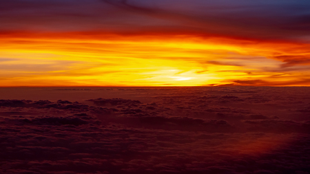 Red and orange sunset above clouds, seen from an airplaneの写真素材