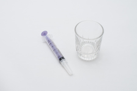 hypodermic syringe and glass measuring cup  isolated on a white background.の写真素材