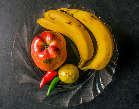 A plate of different fruits like banana, apple,lemon and chills.の写真素材