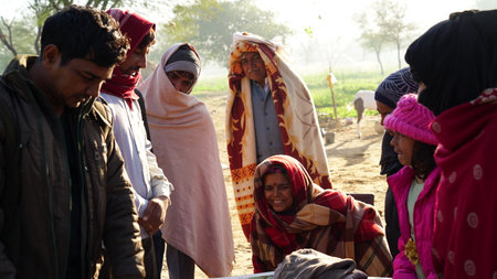 10 January 2021- Chomun, Jaipur, India. Close up portrait of a mature mother and her adult sons seeing a wedding photo album and smiling. Memorable wedding moments concept.のeditorial素材