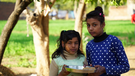 29 December 2020- Badhal, Jaipur, India. Two sibling holding the Laddu sweet in palm. Sibling sister quarreling for Laddu sweet.のeditorial素材