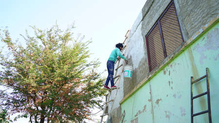 05 February 2021- Khatoo, Jaipur, India. Indian painter renewing the building and doing paint on the wall. Front shot of a man painting wall in his building.の写真素材