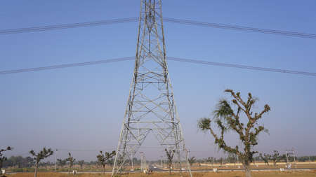 10 February 2021- Sikar, Jaipur, India. Triangular shape iron power supply posts with blue sky nature background. Electricity transmission tower and supply lines closeup.のeditorial素材