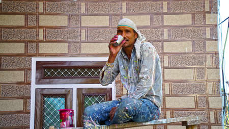 24 February 2021-Khatoo, Jaipur, India. Man with tea. Professional painter redo a living room, have...