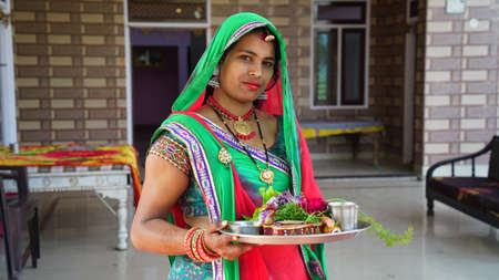 Front shot of Traditional Indian woman holding a sacred plate to pray God. Women with green...