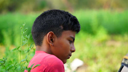 Side view shot of an Little Indian boy with stylish hair cutting. Toddler boy seeing at the camera with attractive black air.の写真素材