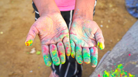 Human hand with Multi colors natural dyes. Flower rose color powder closeup on the human hand. Holi...