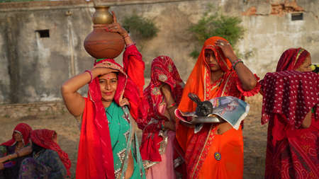 08 April 2021- Reengus, Sikar, India. Two Hindu cultured women with ornamented clothes with a clay...
