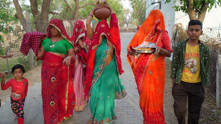 08 April 2021- Reengus, Sikar, India.Religious Hindu women holding sacred water pot on head. Religious Indian women in their traditional attire.のeditorial素材