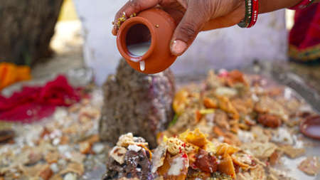 Woman hand offering Milk on Shiv linga statue. Hindu God Shiva milk bathing by a female hand. Hindu...