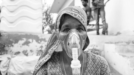 20 May 2021- Reengus, Sikar, India. Old Indian woman infected with Covid 19 disease. Patient inhaling oxygen wearing mask with liquid Oxygen flow.の写真素材