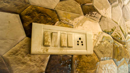 Dirty electricity on off switch with colorful tiles background. Old white light switch.の写真素材