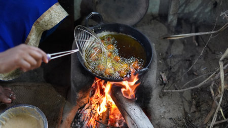 Woman fry food with mustard oil on oven. Typical wood fired oven or chulha used to cook food in rural india.の写真素材