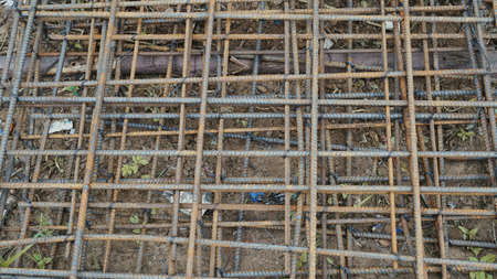 Building under construction waits for concrete slab pouring. Rusty metal wiring is laid on the ground of house under construction.の写真素材