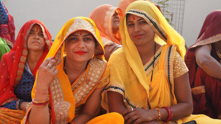 21 November 2021 Reengus, Rajasthan, India. Happy Indian women in yellow saree looking at camera in a wedding programme.のeditorial素材