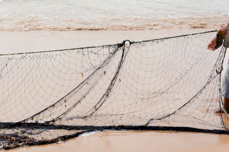 Fishing net being stretched by fishermen after working at sea. City of Salvador, Bahia, Brazil.の写真素材
