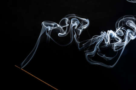 Flavored incense smoke burning. dramatic black background.の写真素材