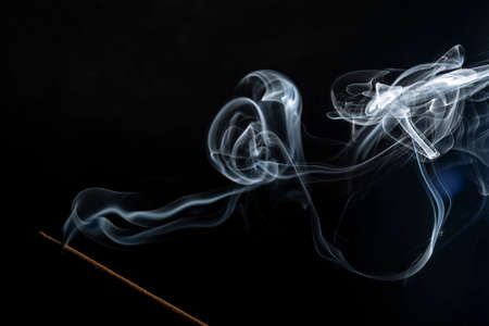 Flavored incense smoke burning. dramatic black background.の写真素材