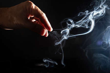 Flavored incense smoke burning. dramatic black background.の写真素材