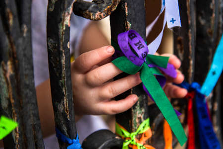 Hands tying the ribbons of Senhor do Bonfim on the iron railing. On the last Friday of the year, masses are held at Igreja do Senhor do Bonfim in Salvador, Bahia, Brazil.の写真素材