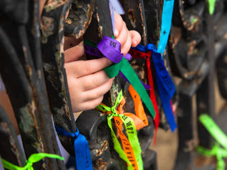 Hands tying the ribbons of Senhor do Bonfim on the iron railing. On the last Friday of the year,...