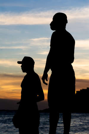 Silhouette of fishermen on the rocks of the Rio Vermelho beach in Salvador, Bahia, fishing for their food and support for their family.の写真素材