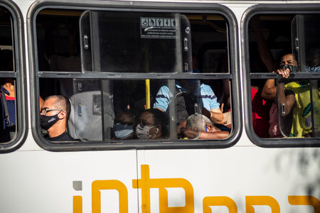 Salvador, Bahia, Brazil - October 21, 2020: Bus packed with people. All wearing protective mask imposed by the coronavirus pandemic. The virus spreads in this closed environment.のeditorial素材