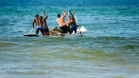 Salvador, Bahia, Brazil - May 23, 2021: Fishermen with oars in the con as entering the sea from Boca do Rio beach.のeditorial素材