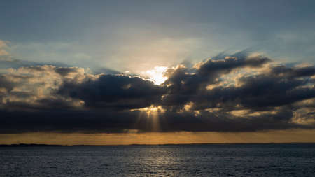Dramatic sunset with yellow cores and heavy clouds in the sea of BaÃ­a de Todos os Santos in Salvador, Bahia, Brazil.の写真素材
