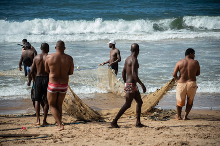 Salvador, Bahia, Brazil - May 23, 2021: Fishermen pulling the fishing net from the sea with fish inside. Boca do Rio beach in Salvador.のeditorial素材