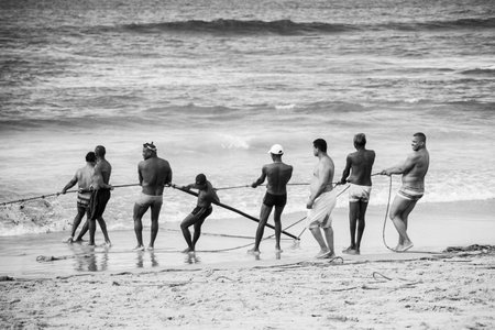 Salvador, Bahia, Brazil - May 23, 2021: Fishermen pulling the fishing net from the sea with fish inside. Boca do Rio beach in Salvador.のeditorial素材