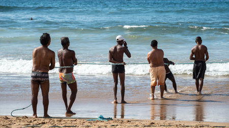 Salvador, Bahia, Brazil - May 23, 2021: Fishermen pulling the fishing net from the sea with fish inside. Boca do Rio beach in Salvador.のeditorial素材